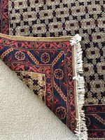 Corner turned up showing backing, material, and white fringe.