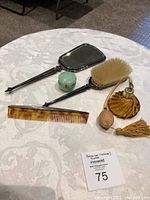 Full view of the set on a white patterned tablecloth showing mirror, brush, comb, perfume bottle and makeup jar.