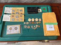 Overview of lot: two sealed coin envelopes, black coin purse, small holders, loose coins and brown envelope