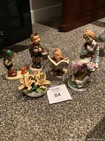 Photo showing complete set of four figurines and small pot of flowers on carpeted floor
