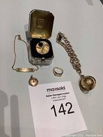 All five jewelry pieces arranged with Birks ring box, ID bracelet, curb chain with ladle, small disc pendant, filigree disc, and signet ring