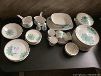 Full view of Noritake dish set showing plates, bowls, cups, creamer, and shakers with floral turquoise pattern.