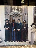 The Beatles photo on the cover of the magazine or record rack showing band members in front of wooden doors.
