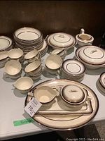 Overview photo showing stack of plates, bowls, covered dishes, creamer, sugar bowl, and a platter with gravy boat