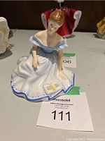 Front view of Royal Doulton Marjorie figurine showing seated woman in white and blue dress holding a book