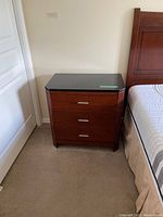 Cherry finish nightstand with black granite top and three drawers