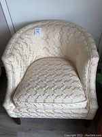 Front view of the Bonaventure tub chair showing cream upholstery with raised chain-link pattern and dark wooden legs.