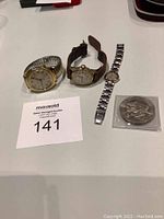 Full group including three watches and silver medallion on white surface.