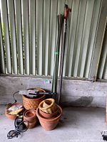View of entire lot showing the electric saw, green gardening stakes, multiple terracotta pots, and wicker baskets.