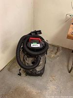 Full view of the Craftsman wet/dry vacuum with a black coiled hose attached and accessories stored on top.