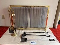 Full view of fireplace screen with brass frame, mesh curtain, and three fireplace tools arranged next to the stand.