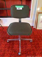 Front view of the forest green upholstered computer chair, showing the cushioned backrest and seat, metal base with casters.