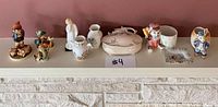 Overview of nine porcelain items including Hummel figurines, Royal Doulton figurine, Aynsley vases, cream lidded dish, Japanese figurine and dish on mantle