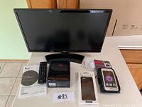 LG TV displaying with remote control and safety manual on table, Powerbeats 2 Wireless headphones box in front