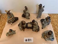 Group shot of all seven porcelain figurines on paper background