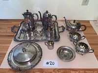 Photo of the full tea set and serving ware arranged showing all items including two pots on the tray, cream/sugar dishes, covered platter, and small tray.
