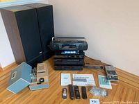 Full lot overview showing speakers, stacked stereo components, portable units, manuals and cables