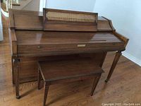 Front view of Baldwin upright piano with top panel closed and matching bench