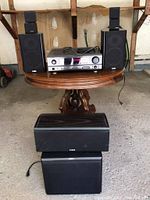 Full view of audio receiver and speakers arranged on wooden table including subwoofers, main speakers, and satellite speakers.