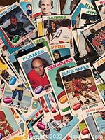 Close-up of a variety of individual hockey cards from 1970s featuring prominent players and teams like Flames, Canadiens, Black Hawks, Sabres.