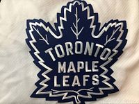 Close-up of blue Toronto Maple Leafs logo on white mesh jersey fabric