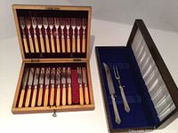 Two-piece carving set with fork and two knives in velvet-lined black box with satin interior.