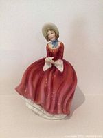 Front view of Royal Doulton Denise figurine showing detailed face, bonnet, and red dress with white cuffs.