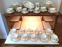 Complete view of all pieces from the tea set arranged on wood surfaces showing the quantity and types of items.