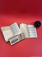Two open blue stamp booklets showing mint Canada stamps, Sucrets box and wrappers visible