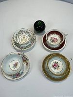 Overview of all four Paragon cup & saucer sets around green glass paperweight