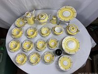 Top-down view of full set on table showing pots, serving pieces, cups, saucers and plates.