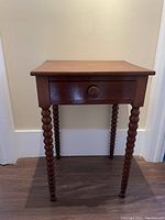 Front view of the cherry side table showing the drawer and bobbin-turned legs