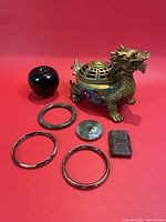Full view of cloisonne censor, jade bangles, carved plaques, and dark carved object on red background