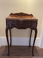 Front full view of ornate carved cabriole leg telephone table showing drawer and backboard carving