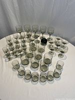 Overview of the entire Orrefors vintage smoke glassware set arranged on a white tablecloth showing various types and sizes of glasses.
