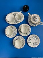 Overhead view of entire tea service showing teapot with lid, tray with sugar bowl and creamer, three cups and four saucers