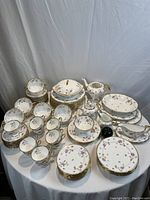 Overhead shot of the complete dinnerware set on table showing plates, cups, saucers, bowls, serving pieces.