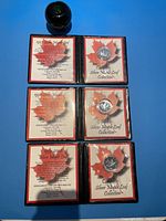 Three open presentation cases showing certificate pages and coins side by side with green apple for scale