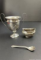 Golf trophy cup, salt cellar, and salt spoon arranged on black background