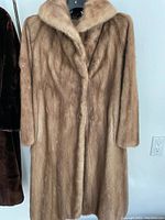 Full-length beige mink coat hanging front view