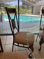 Side profile of a heavy duty metal and cloth dining chair by the poolside, showing the overall shape and fabric seat.