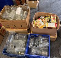 Overview photo showing four boxes containing clear glass canning jars and boxes of lids.