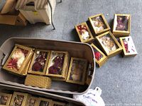 Several Christmas dolls and figurines boxed in decorative packaging inside a large plastic tub.