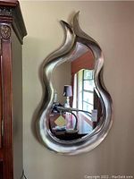 Frontal view of flame-shaped decorative composite mirror hanging on the wall.