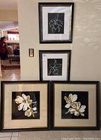 Four framed floral art prints displayed on wall and floor; two smaller line art prints above two larger realistic floral prints.