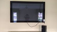 Front view of 62-inch Elite plasma television with speaker visible beside it and hanging power cord.