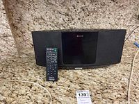 Front view of Sony tabletop radio with CD/iPod player showing black speaker grille and remote control placed in front.