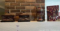 Photo showing two dark wood carved decorative boxes with finial tops, one ornate urn with finial, and two mosaic patterned tall rectangular boxes.