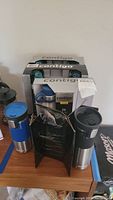 Photo showing three Contigo insulated travel bottles/cups, two out of box and one in original packaging with visible logo and product info