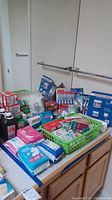 Wide view of first aid and personal care items including band aids, gauze, cotton balls, bottles, toothpaste, and sanitary pads arranged on a counter